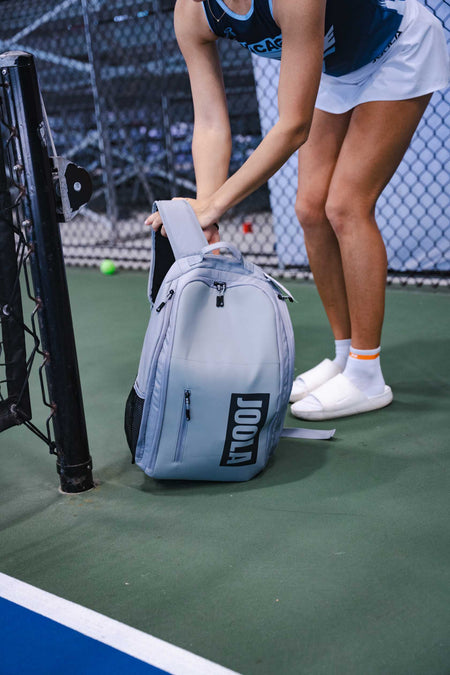 Person on a pickleball court with a gray JOOLA Vision II backpack. 