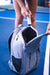 Person opening a JOOLA pickleball backpack on a pickleball court,