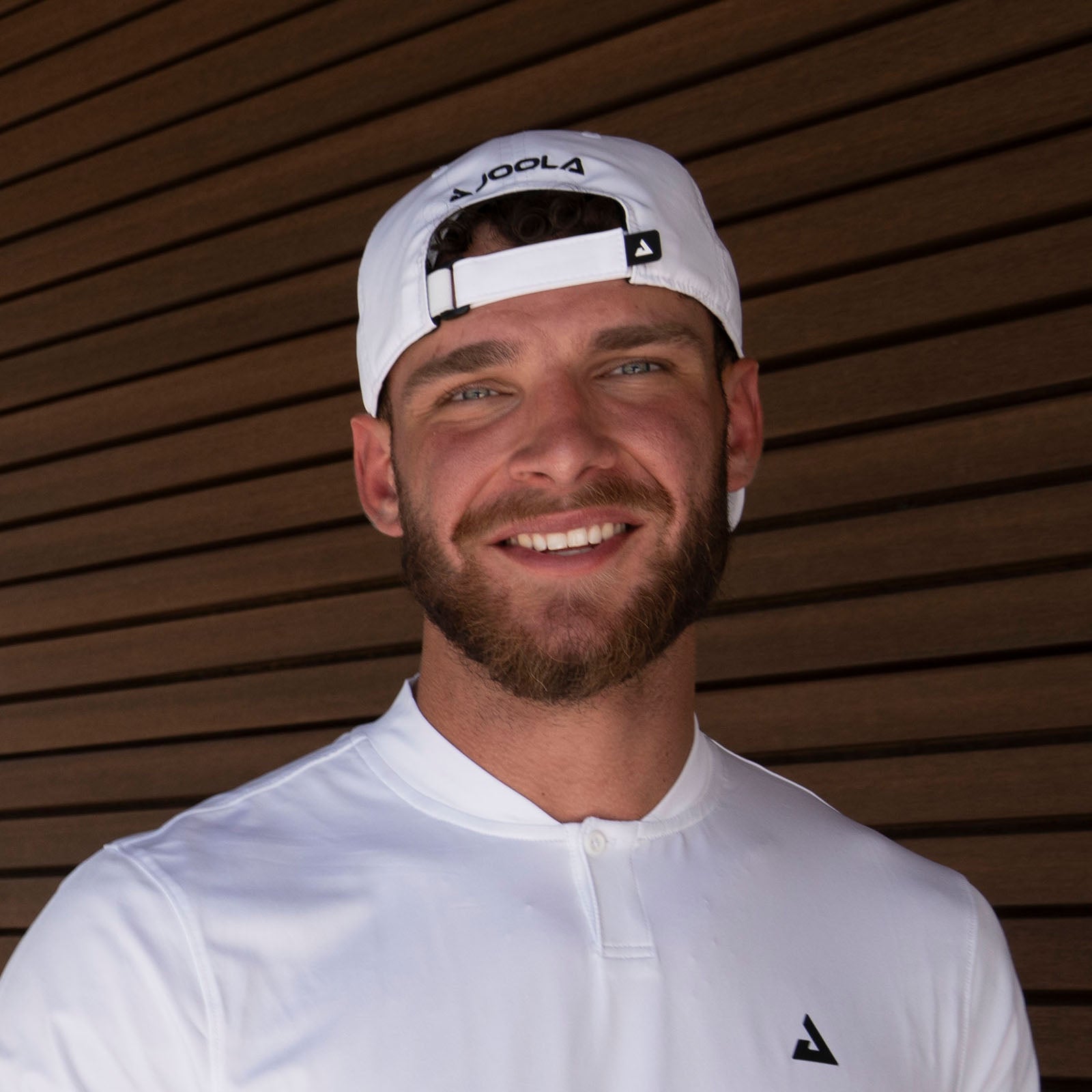 Male model wearing the JOOLA Essential Hat backwards, white.