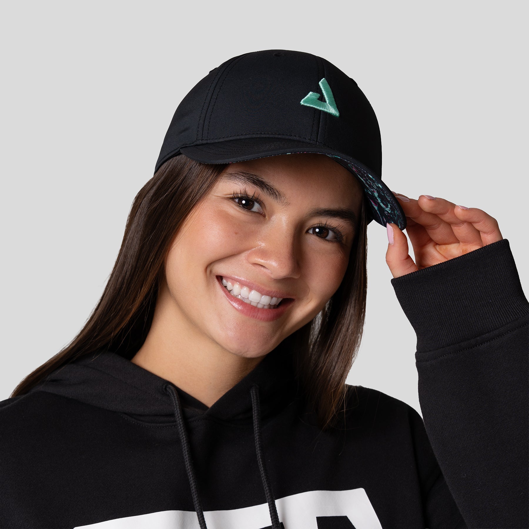 Female model wearing a JOOLA Essential hat black with cool print.