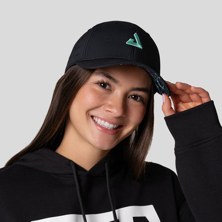 Female model wearing a JOOLA Essential hat black with cool print.