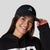 Female model wearing a JOOLA Essential hat black with cool print.