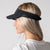 A side profile view of a female model wearing a JOOLA Essential Visor, black.