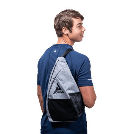 White Background Image: Image of Ben Johns wearing the JOOLA Essentials Sling Bag over his shoulder.