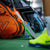 Orange sports bag, green pickleball paddle, and yellow shoes on a green surface with blurred background