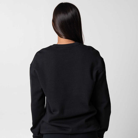 Gray background, image of the back of a female model who is wearing a black fleece crew.