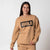 Gray background, image of a female model wearing the JOOLA Fleece Crew and matching Fleece Pants, Latte Colored.
