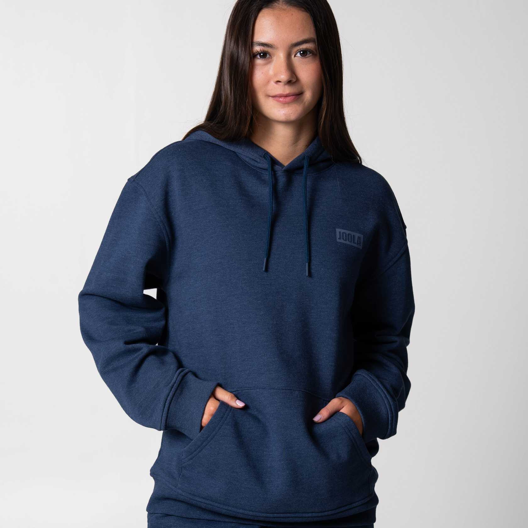 Gray background, image of a female model wearing a JOOLA Fleece Hoodie, Navy.