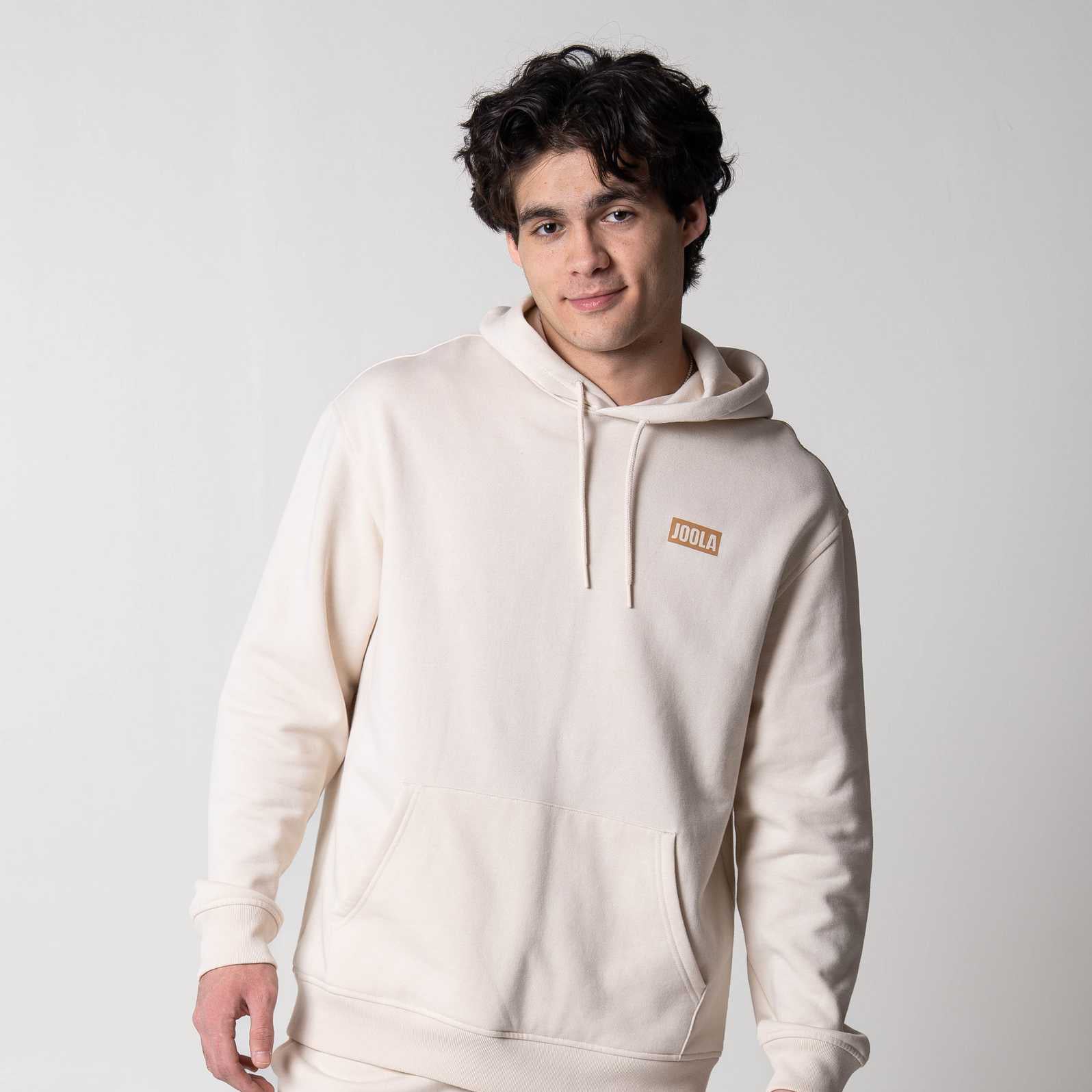 Gray backround, image of a male model wearing a JOOLA fleece hoodie.