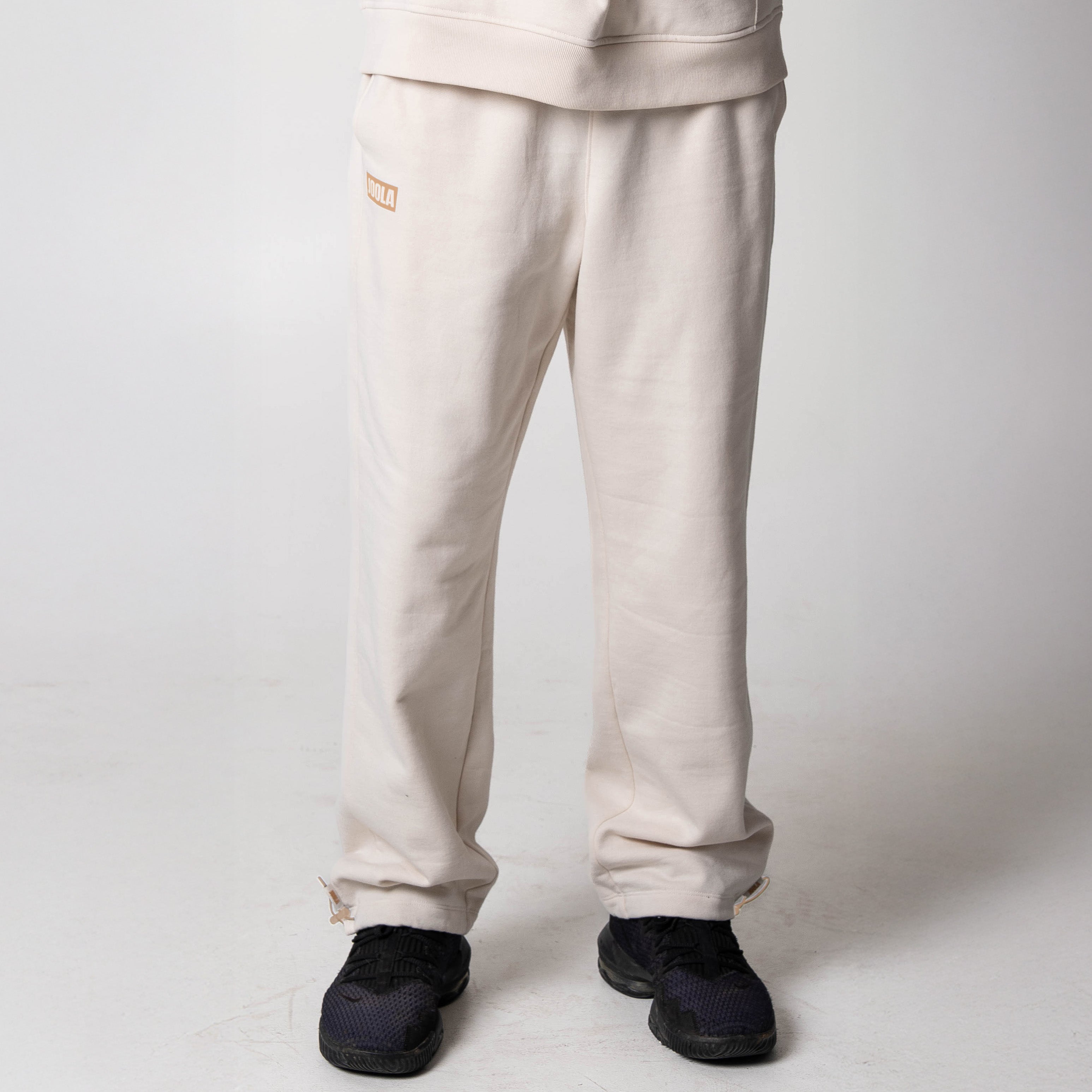 Gray background, image of a pair of sandstone colored JOOLA fleece pants.