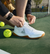 Pickleball player tying their JOOLA R4LLy pickleball shoe, from the Core collection, the shoe is the R4LLy Men's White shoe.