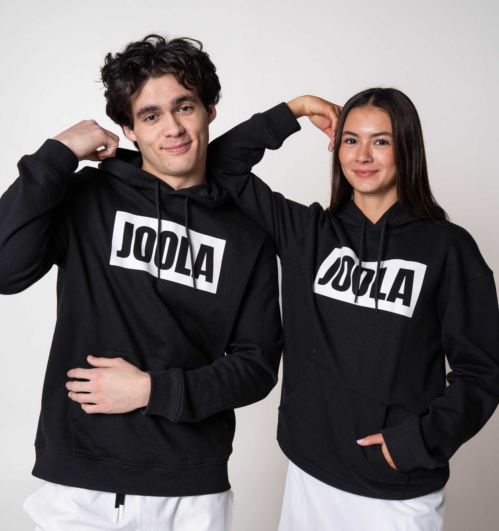 Two models posing in matching JOOLA Graphic Hoodies, Black and White.