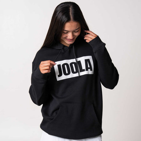 Gray background, female model wearing a JOOLA Graphic Hoodie, Black and White.
