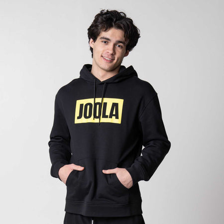 Gray background, image of a male model wearing a black JOOLA Graphic hoodie.