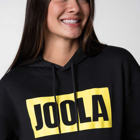 Close up on the yellow and black JOOLA logo on the front of a JOOLA graphic hoodie, black and yellow.