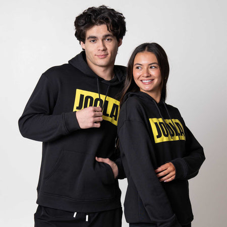 Gray background, two models wearing JOOLA Graphic Hoodies, Black with Yellow JOOLA logo.