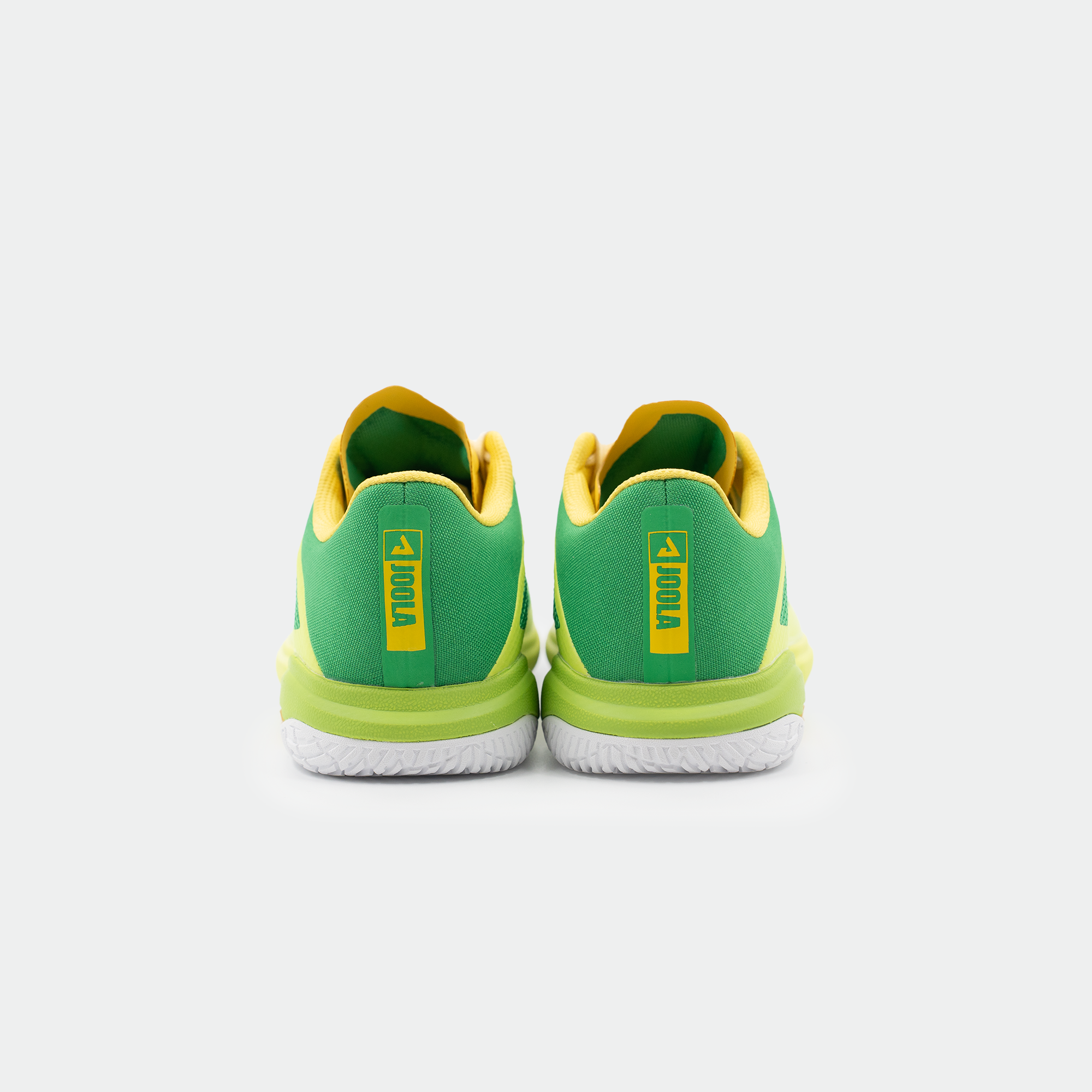 White background, product image of the JOOLA TT SM4SH table tennis, green, yellow and white colorway. Image shows the back of a pair of the shoes, with JOOLA logo lock up.