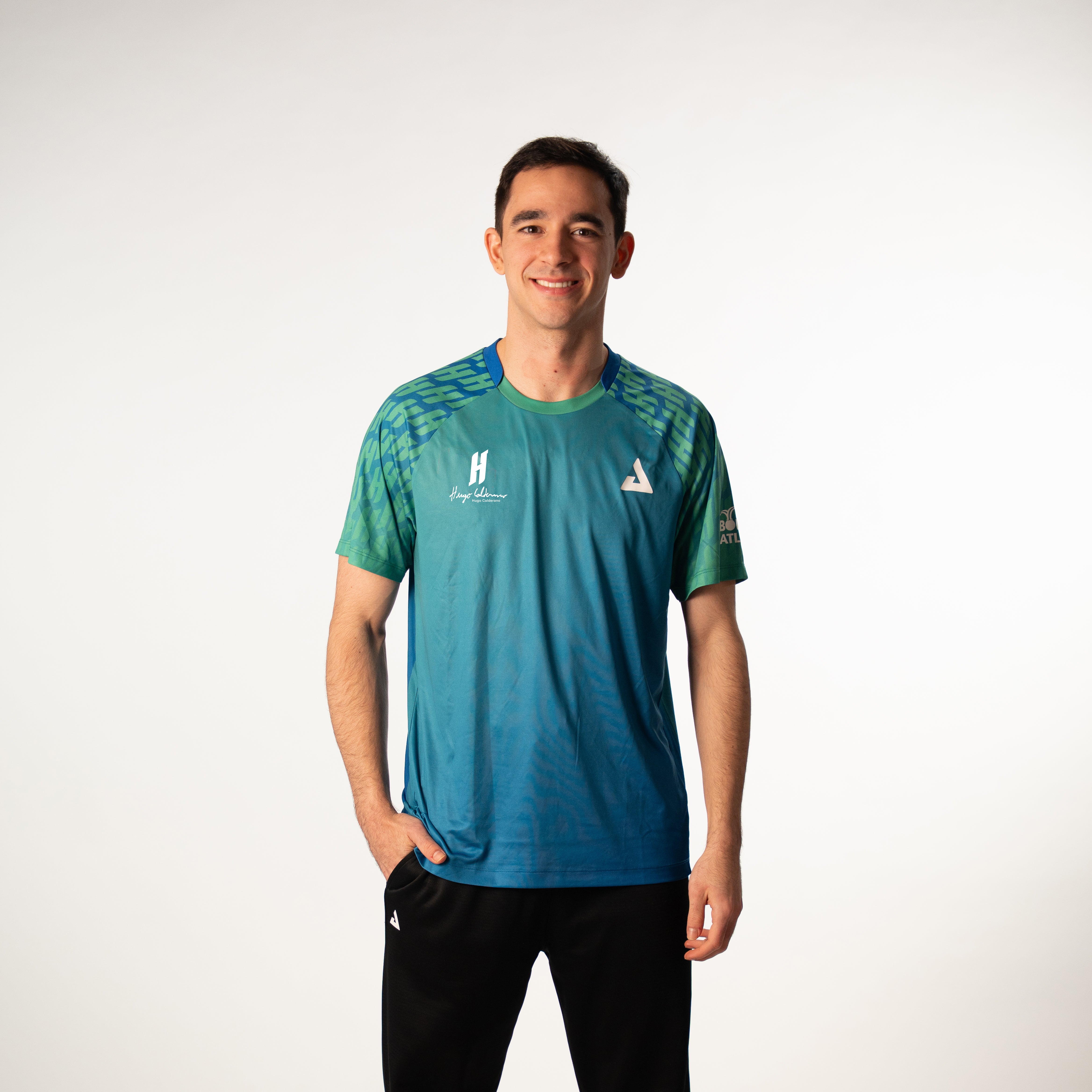 White background, image of Hugo Calderano wearing a Hugo Calderano Gradient Monogram Raglan Short Sleeve shirt.