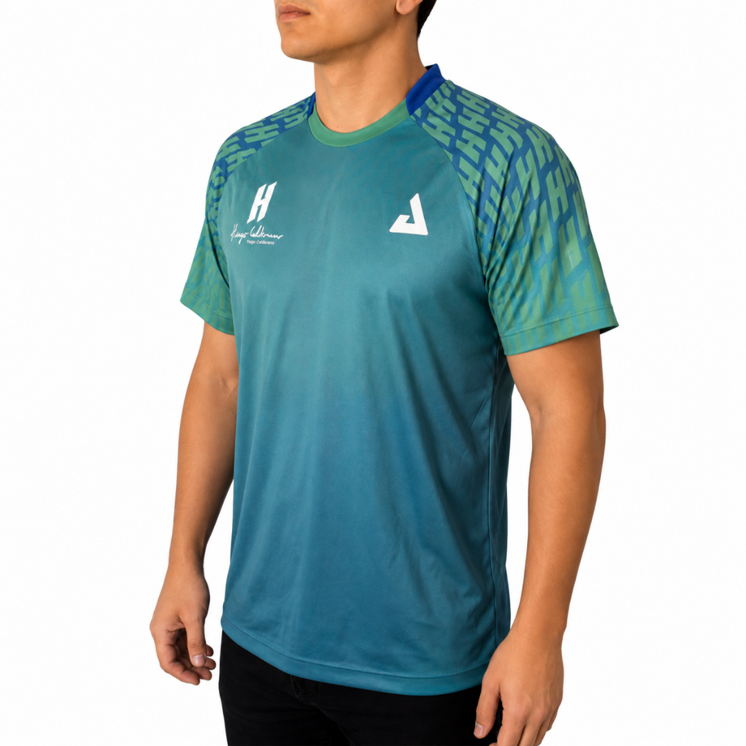 White background, image of Hugo Calderano wearing a Hugo Calderano Gradient Monogram Raglan Short Sleeve shirt.