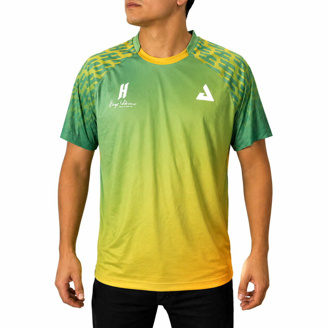 White background, image of Hugo Calderano wearing a Hugo Calderano Gradient Monogram Raglan Short Sleeve shirt. Jungle Green colorway.