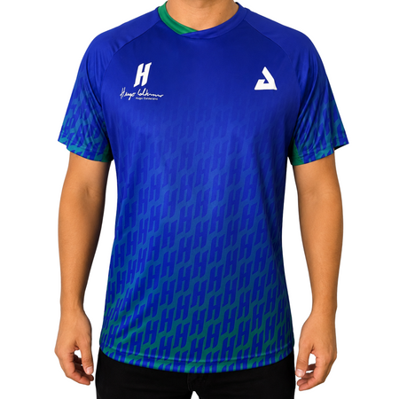 White background, image of a male model wearing a Hugo Calderano Monogram Crossover Raglan Short Sleeve shirt, Azul.