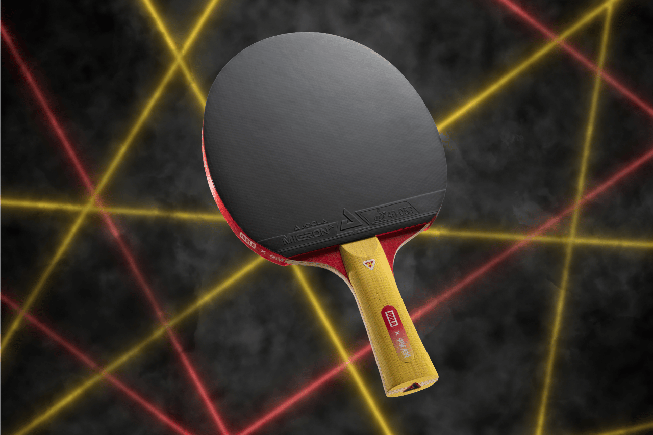 Floating image of the JOOLA x Steve Aoki HiroQuest Table Tennis Racket, yellow handle and black racket face.