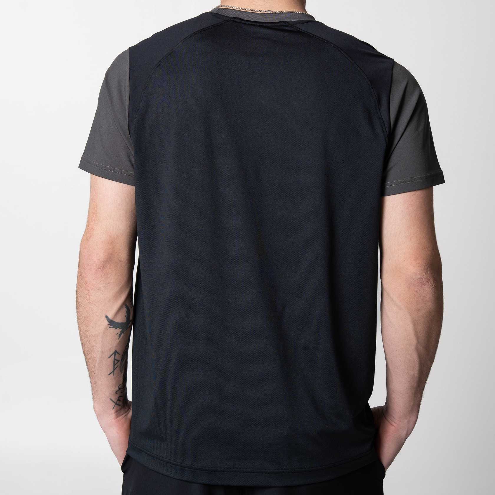 White backround, the back of a model wearing a JOOLA Hybrid Short Sleeve shirt, Charcoal colored.