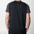 White backround, the back of a model wearing a JOOLA Hybrid Short Sleeve shirt, Charcoal colored.