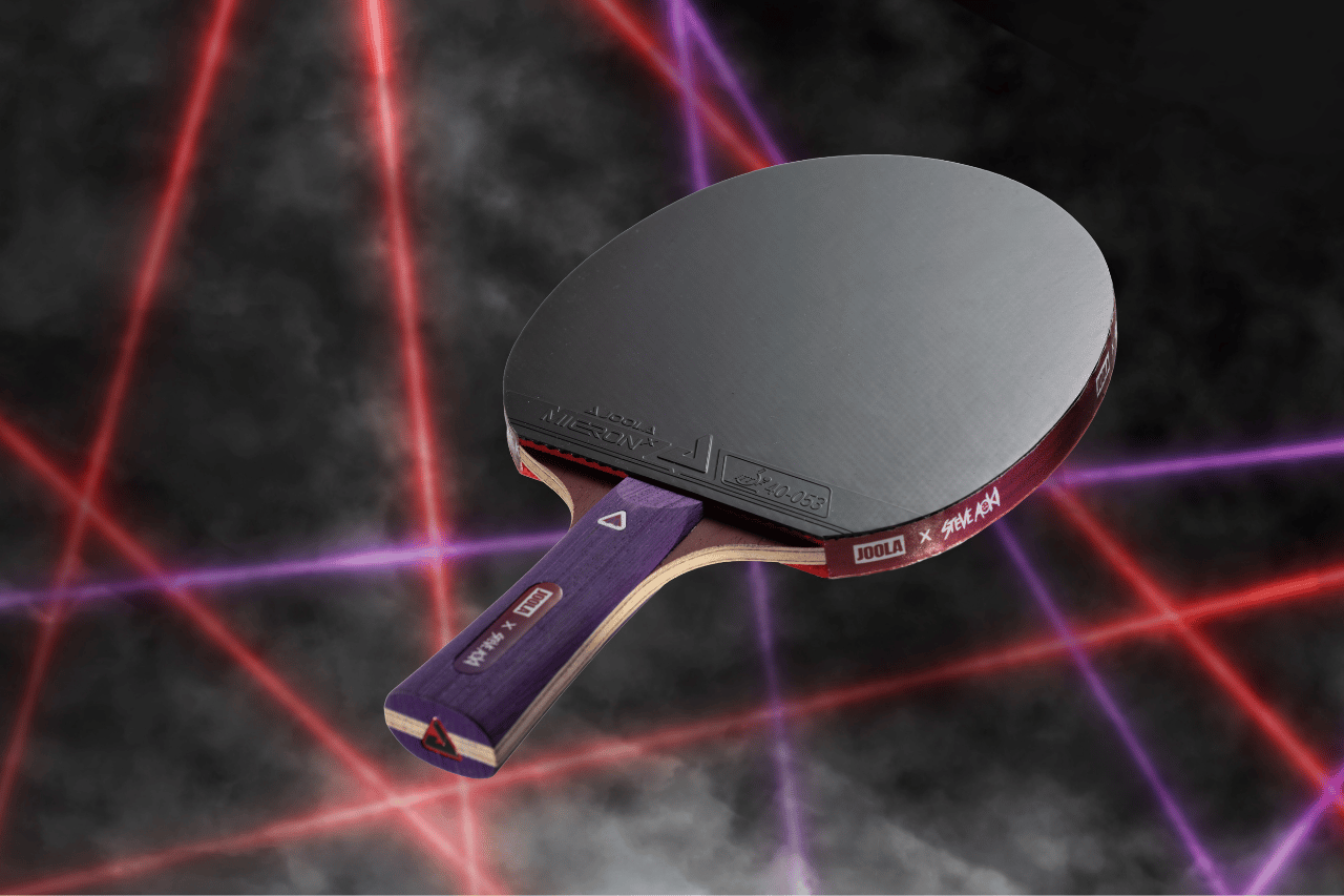 Floating image of the JOOLA x Steve Aoki Hyro Table Tennis racket. The background has red and purple lasers and smoke.