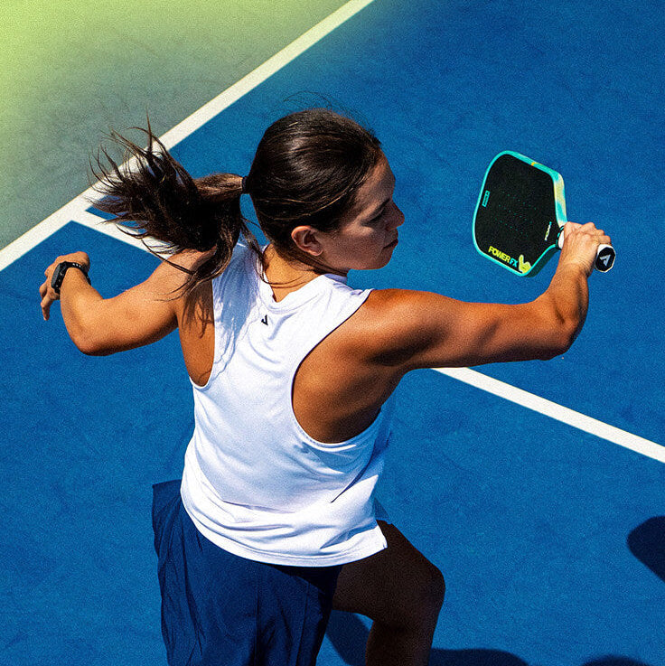 Stylized image of a female pickleball player on a blue court swinging through the ball witht he JOOLA Power FX pickleball paddle.