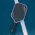 Image of the JOOLA Pink Perseus 3S pickleball paddle shown at an angle on the pickleball court.