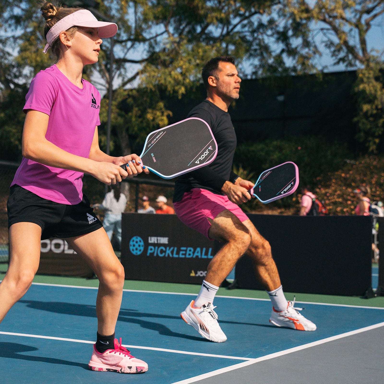 Image of two JOOLA players with JOOLA Pink Perseus pickleball paddle in their hands.