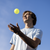 Man preparing to serve a pickleball against a clear blue sky