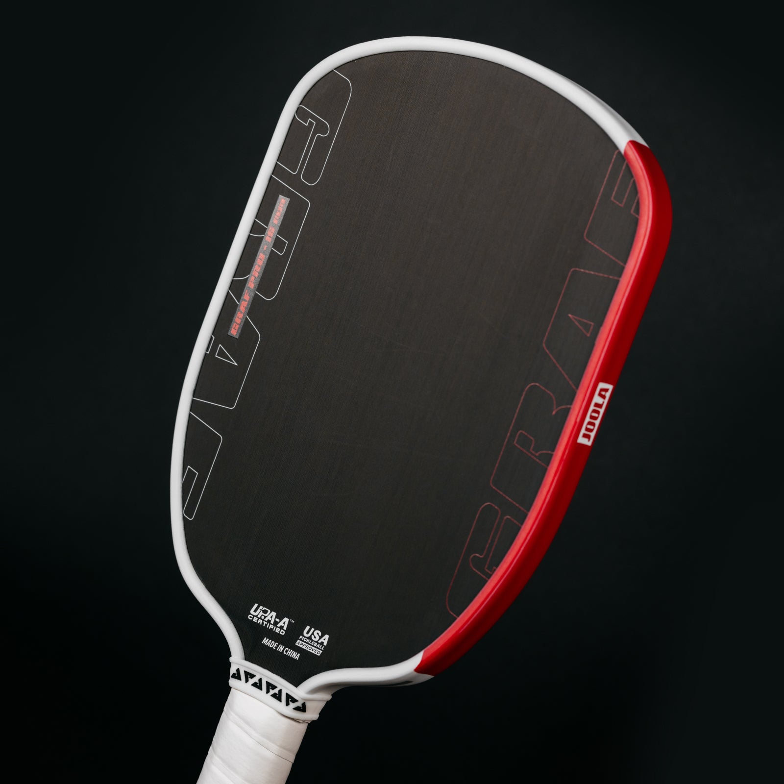 Black background, Agassi x JOOLA Graf Pro pickleball paddle with black surface, white handle and red and white edge guard.