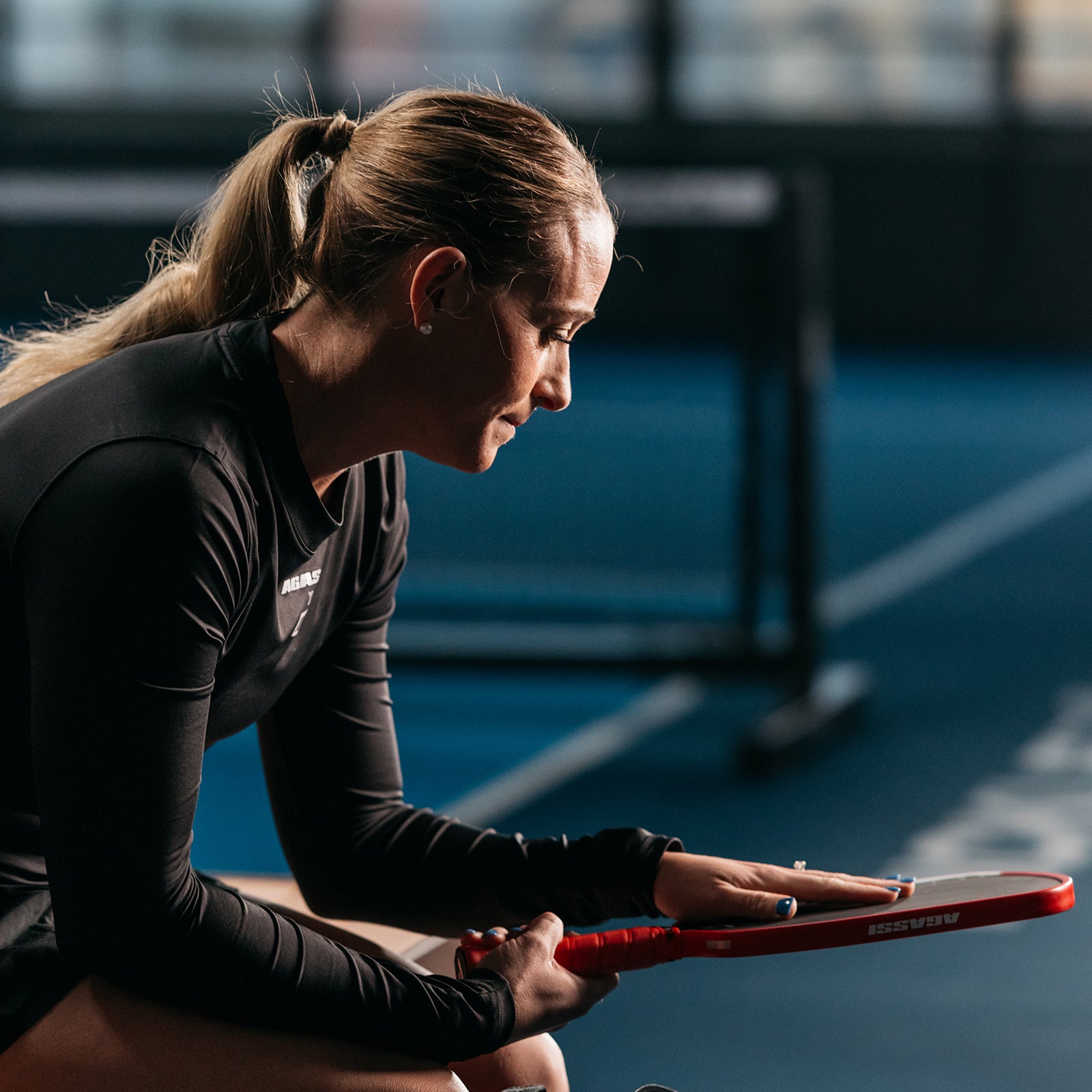 Close up image of Brooke Buckner sitting down and feeling the surface of the Agassi x JOOLA Agassi Pro Pickleball Paddle.