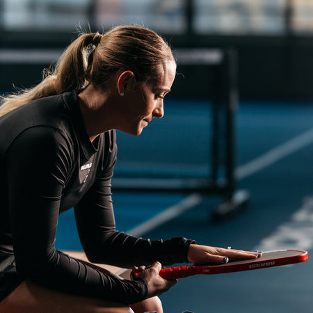 Close up image of Brooke Buckner sitting down and feeling the surface of the Agassi x JOOLA Agassi Pro Pickleball Paddle.