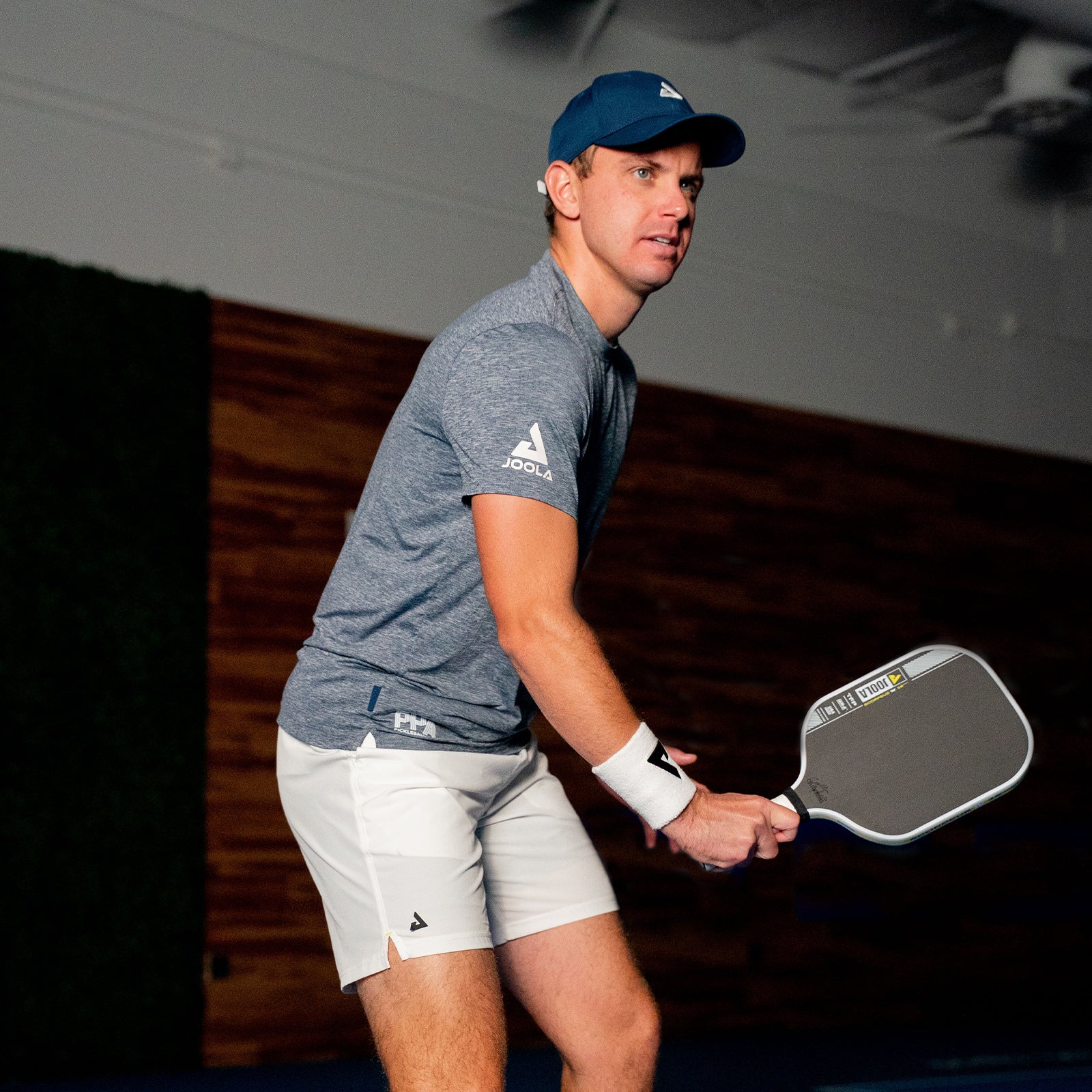 Image of JOOLA Pro Collin Johns holding the JOOLA Collin Johns Scorpeus Pro IV Pickleball Paddle at an indoor facility. 16mm.