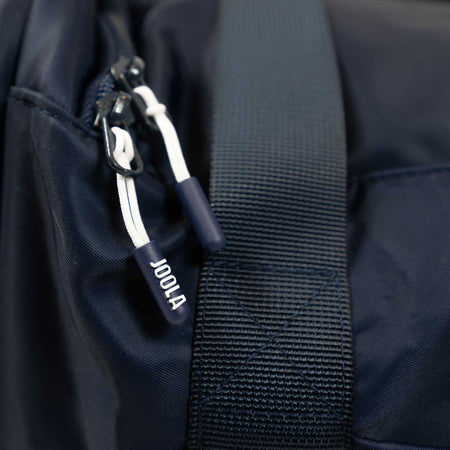Close-up of a black backpack with a visible JOOLA brand logo on a dark background