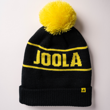 White background, image of a JOOLA pom pom beanie, black and yellow.