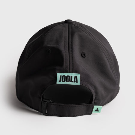 Black cap with JOOLA logo on a light gray background, logo and tag are tourquiouse. 