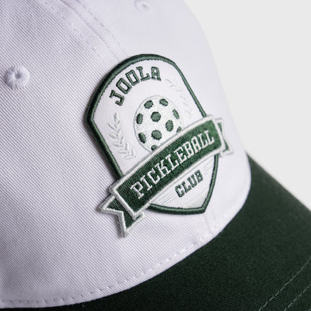 White and green JOOLA Collegiate cap with pickleball club logo on a light gray background