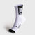 A single white crew sock with black accents, featuring a black cuff panel with the word 'JOOLA' in white and a black toe cap, shown on a light gray background.