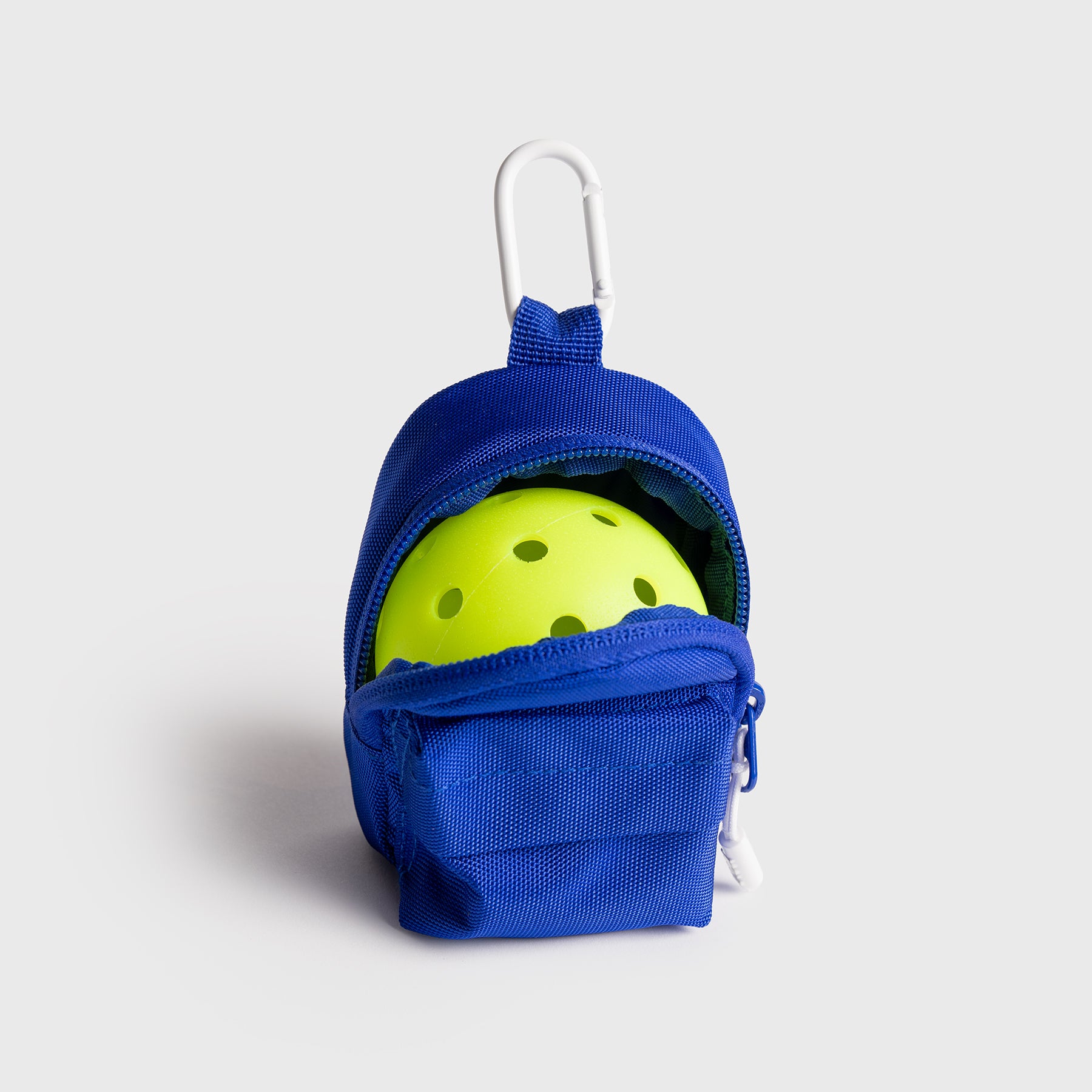 Blue JOOLA Micro bag with carabiner, open with a single pickleball inside, on a light gray background.