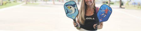 Banner image of female JOOLA pro holding two JOOLA Junior Series Pickleball Paddles.