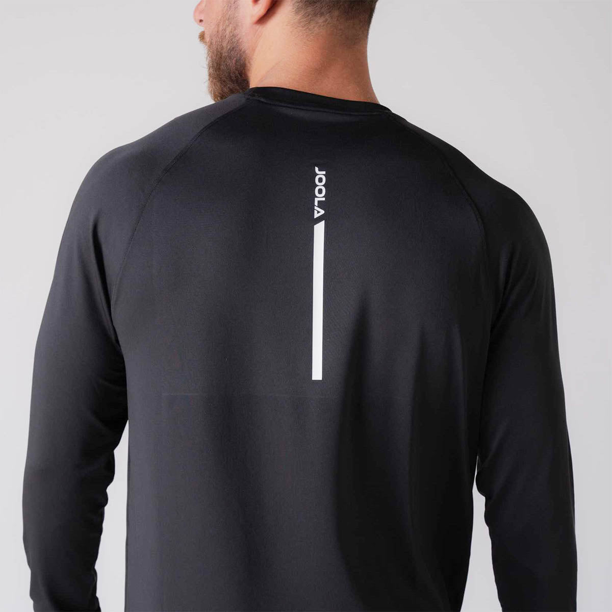 Close up image of the back of a male model wearing a JOOLA Men's Court Long Sleeve Shirt, Black. Back shows the JOOLA logo.