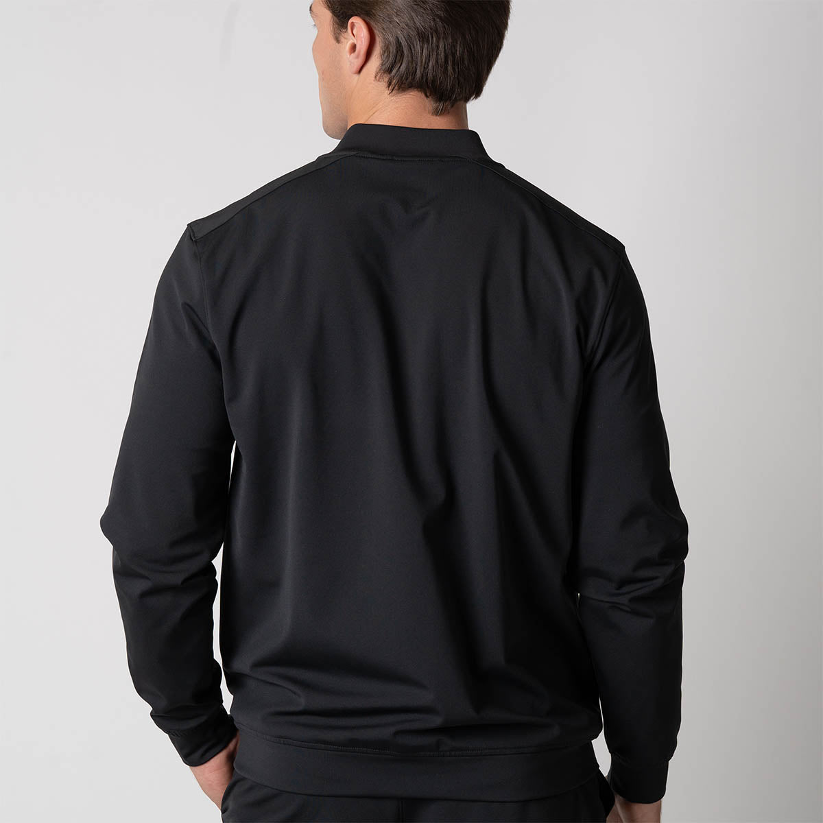 Image showing the back of a male model who is wearing a JOOLA Men's Warm Up Jacket, Black.