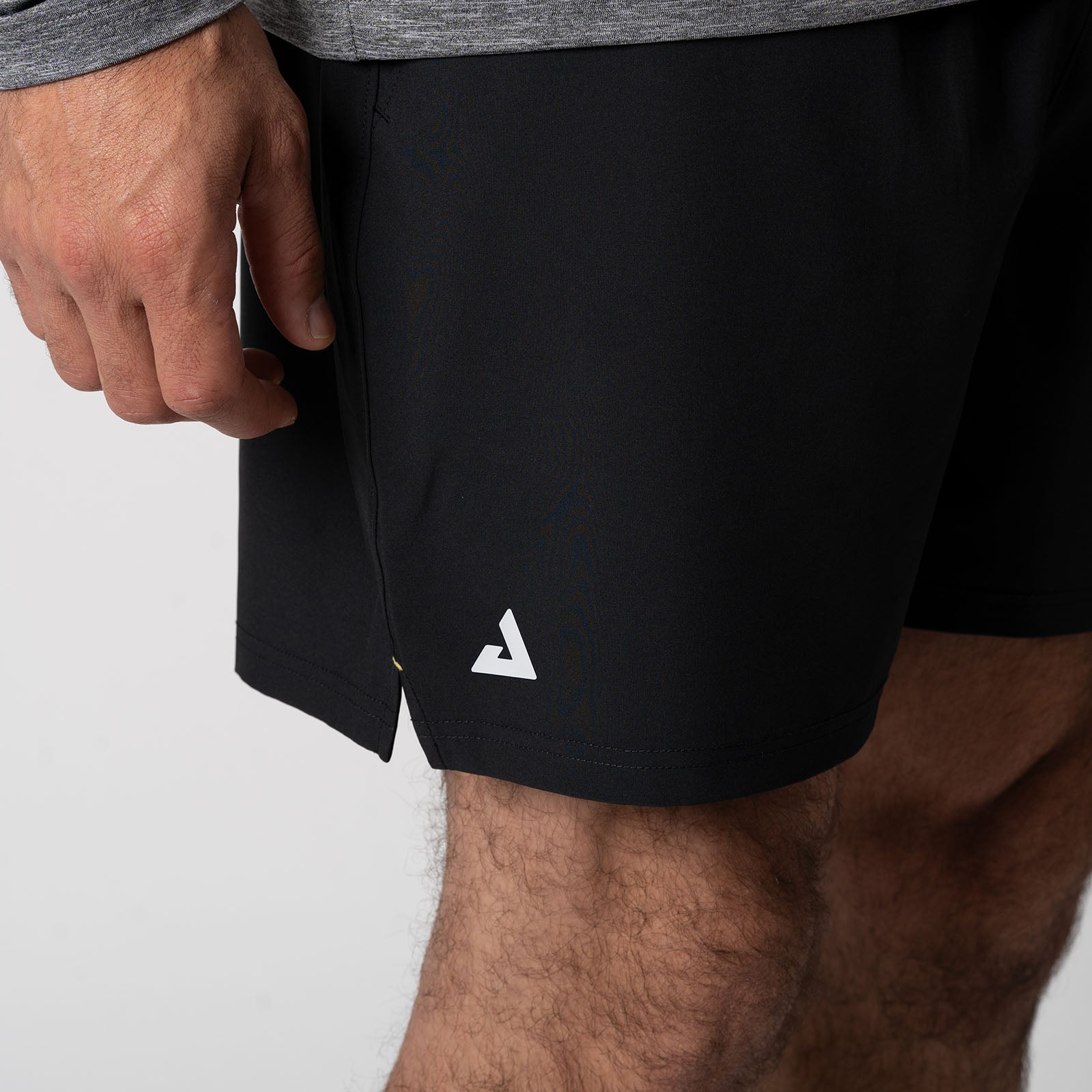 Close up image of the JOOLA Trinity logo on the leg of a pair of JOOLA Men's Woven Shorts, black.