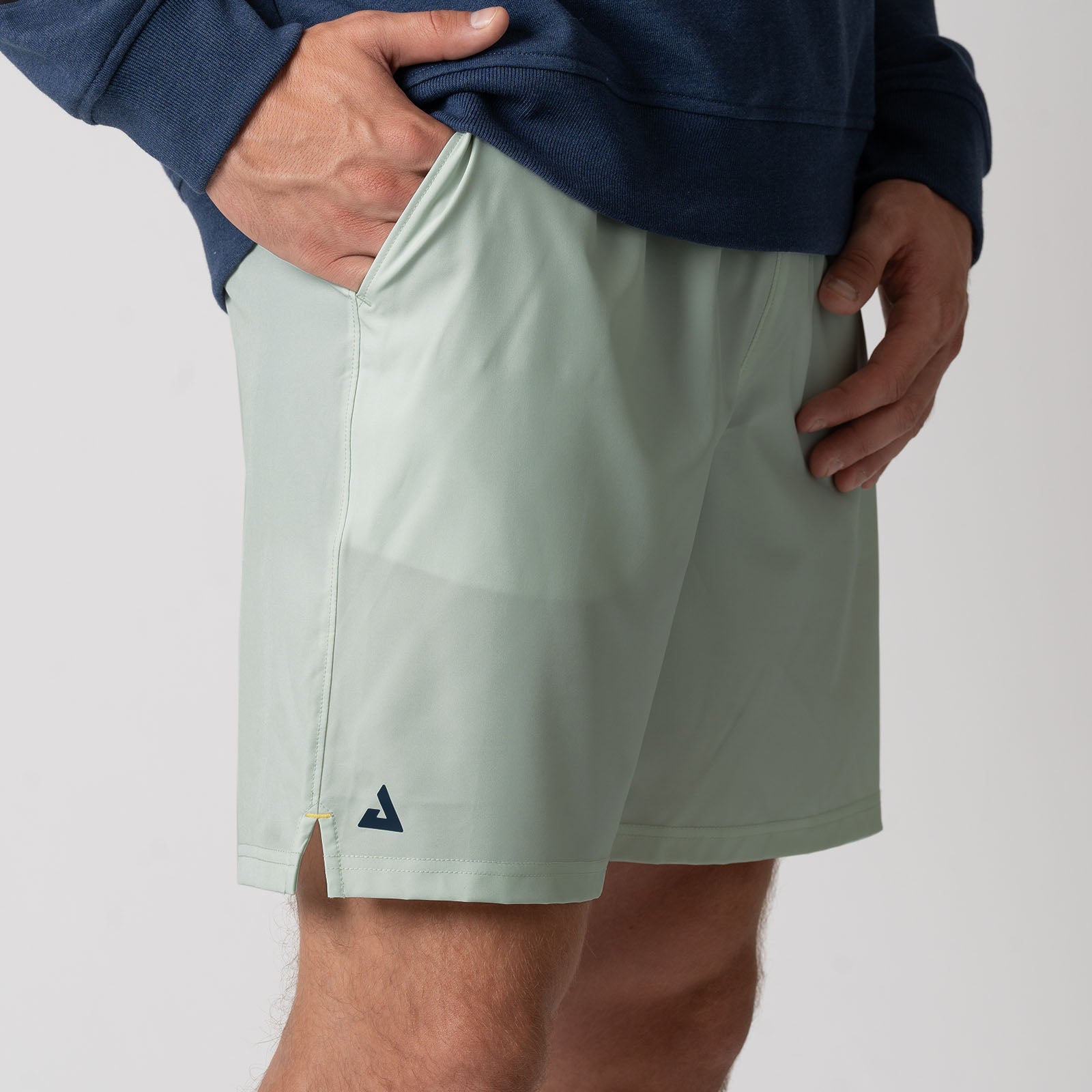 Close up image showing the JOOLA trinity logo on the leg of a pair of JOOLA men's woven shorts, 7 inch inseam, hushed mint.