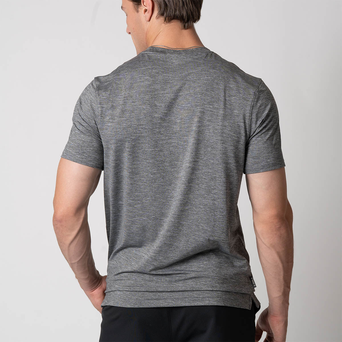 Image showing the back of a male model who is wearing a JOOLA Men's Club Short Sleeve Shirt, Charcoal Heather.