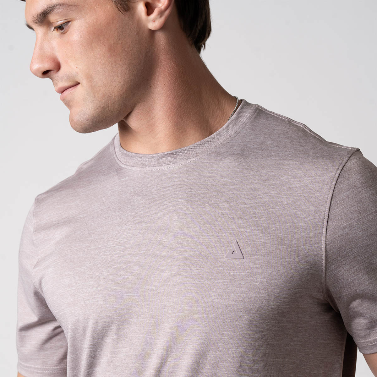 Close up image showing the JOOLA logo over the left chest of a male model who is wearing a JOOLA men's club short sleeve shirt, dusty mauve.